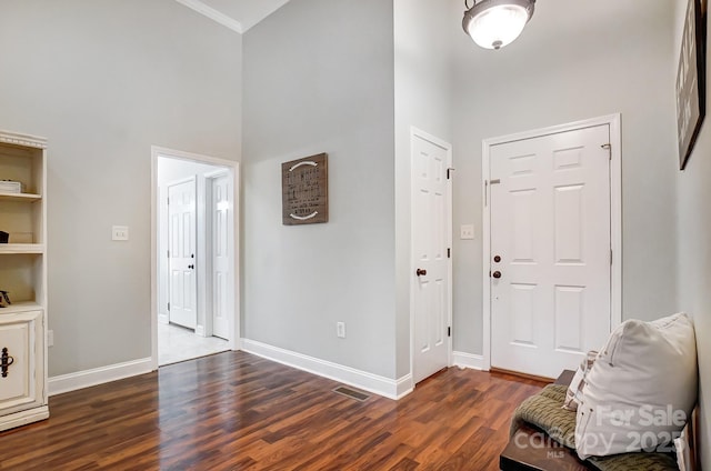 foyer with ornamental molding, a towering ceiling, and dark hardwood / wood-style flooring