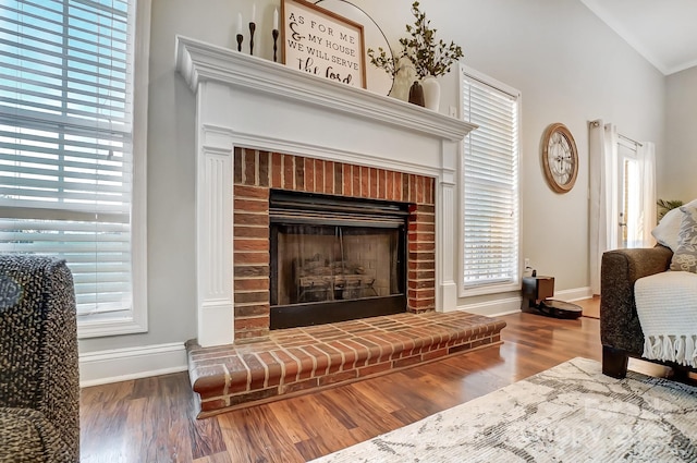 living area featuring wood-type flooring, lofted ceiling, and a fireplace