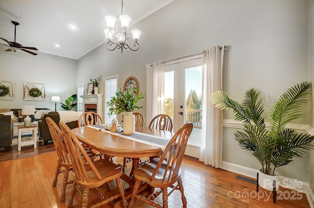 dining area with hardwood / wood-style flooring, ceiling fan, high vaulted ceiling, and french doors