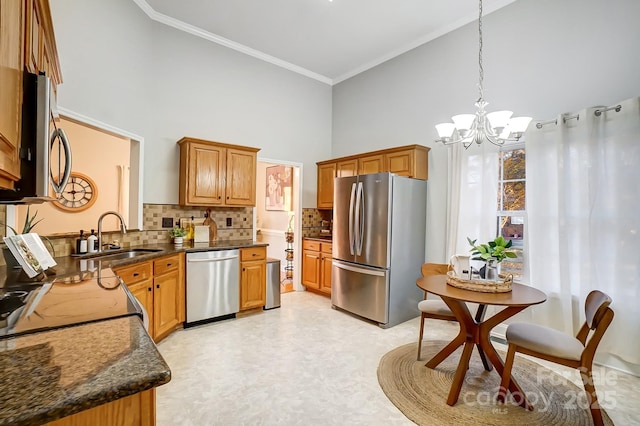 kitchen with sink, pendant lighting, a towering ceiling, stainless steel appliances, and backsplash