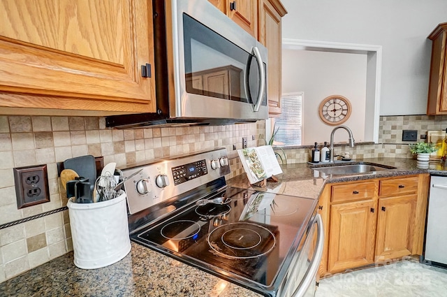 kitchen with tasteful backsplash, sink, stainless steel appliances, and dark stone counters