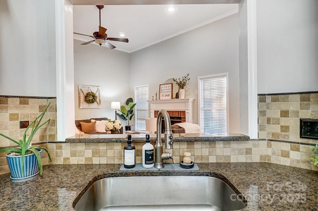 kitchen with a brick fireplace, crown molding, sink, and ceiling fan