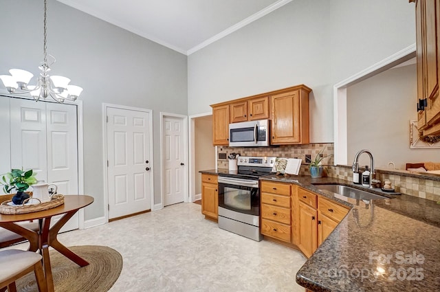 kitchen featuring sink, ornamental molding, appliances with stainless steel finishes, pendant lighting, and a high ceiling