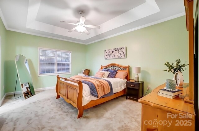 bedroom featuring a raised ceiling, crown molding, light carpet, and ceiling fan