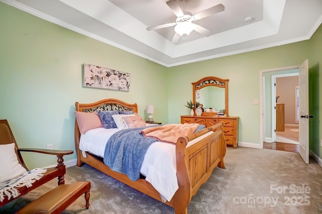 bedroom with ornamental molding, carpet floors, ceiling fan, and a tray ceiling