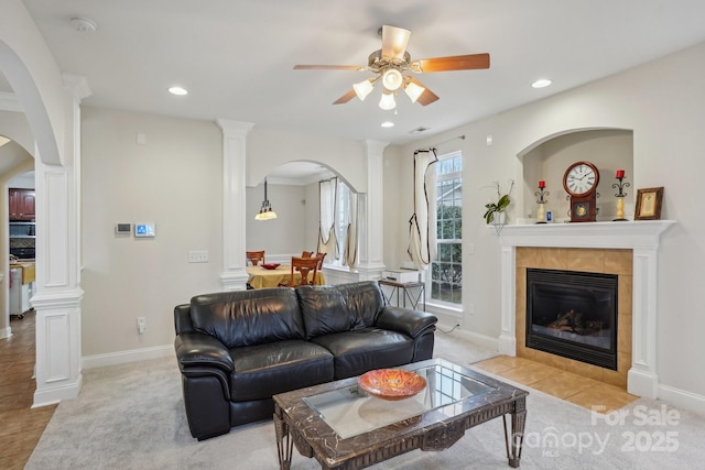 living area featuring arched walkways, recessed lighting, a tile fireplace, and ceiling fan