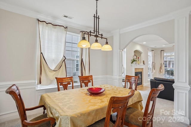 dining area featuring visible vents, arched walkways, a glass covered fireplace, and a wainscoted wall