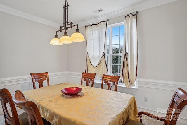 dining area featuring visible vents, ornamental molding, wainscoting, and a decorative wall