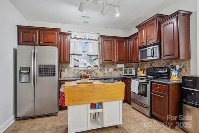 kitchen featuring dark countertops, visible vents, tasteful backsplash, a kitchen island, and stainless steel appliances