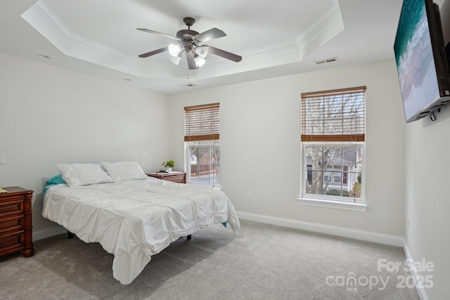 carpeted bedroom with a tray ceiling, baseboards, visible vents, and crown molding