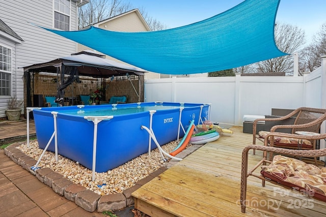 view of swimming pool featuring a gazebo, a fenced in pool, a fenced backyard, and a wooden deck