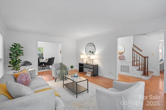 living room featuring crown molding and light hardwood / wood-style flooring