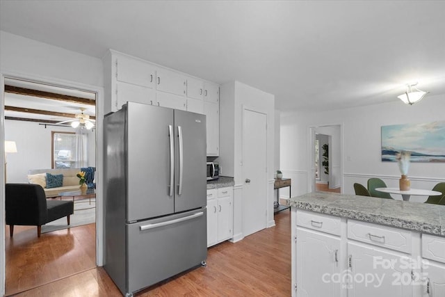 kitchen with white cabinets, stainless steel appliances, beamed ceiling, light hardwood / wood-style floors, and ceiling fan