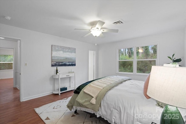 bedroom with ceiling fan, dark wood-type flooring, and multiple windows