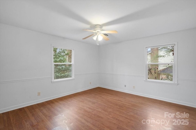 empty room featuring ceiling fan, a wealth of natural light, and hardwood / wood-style floors