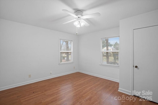 empty room with ceiling fan, a wealth of natural light, and hardwood / wood-style floors