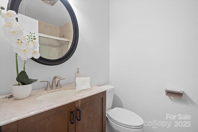 bathroom featuring vanity, toilet, and a shower with door