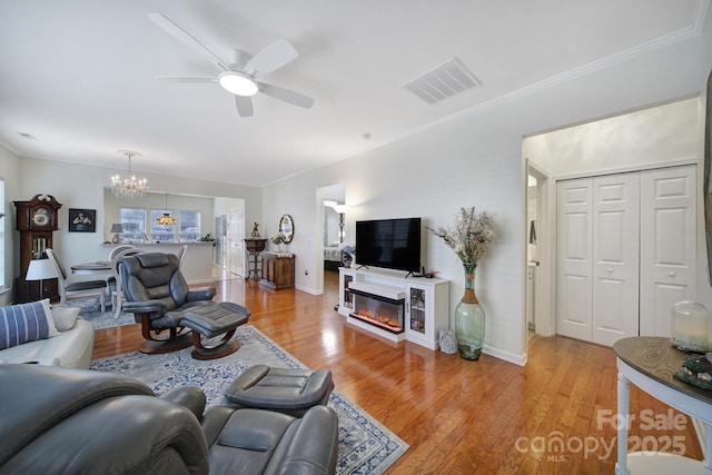 living room featuring ceiling fan with notable chandelier and light hardwood / wood-style flooring