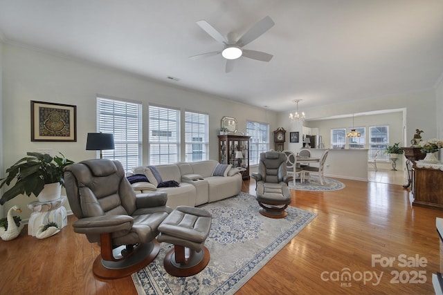 living room with ceiling fan with notable chandelier and light wood-type flooring