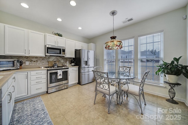 kitchen featuring stainless steel appliances, white cabinetry, decorative backsplash, and pendant lighting