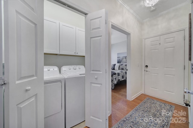 laundry room with washer and clothes dryer, ornamental molding, light hardwood / wood-style floors, and cabinets