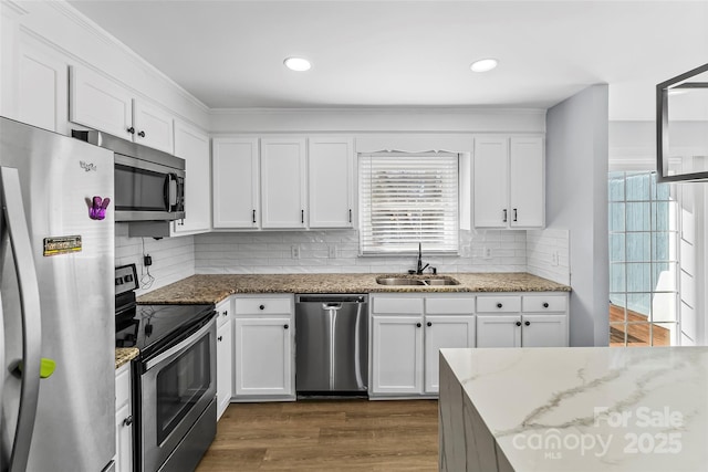 kitchen with light stone counters, stainless steel appliances, decorative backsplash, white cabinets, and sink