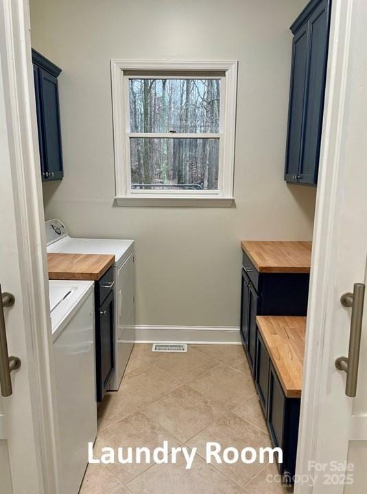 clothes washing area with washer and dryer, cabinets, and light tile patterned floors