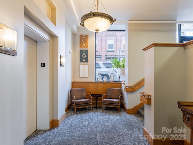 living area featuring plenty of natural light, dark carpet, and elevator