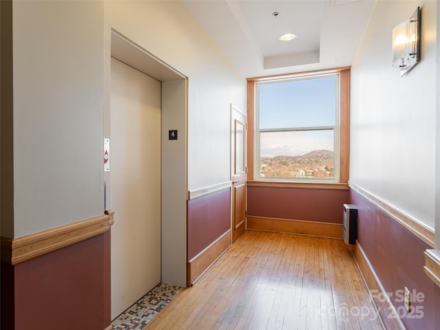 corridor with elevator and light wood-type flooring