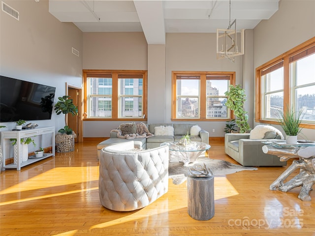 living room with plenty of natural light, an inviting chandelier, and light wood-type flooring