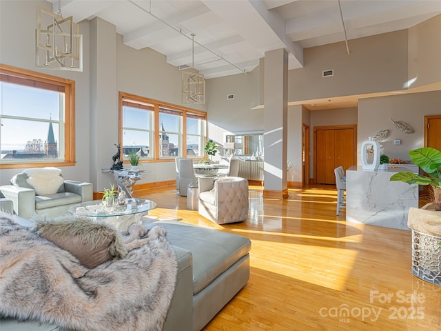 living room with beamed ceiling, hardwood / wood-style floors, a wealth of natural light, and a high ceiling