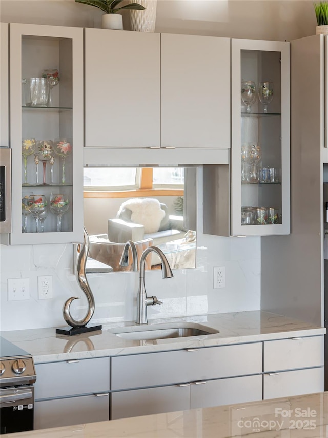 kitchen featuring decorative backsplash, stainless steel electric range, light stone counters, and sink