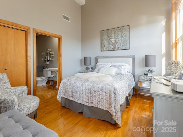 bedroom featuring hardwood / wood-style floors, a towering ceiling, and a closet