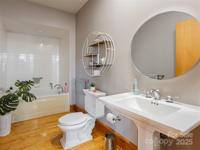 bathroom featuring a tub to relax in, sink, hardwood / wood-style floors, and toilet