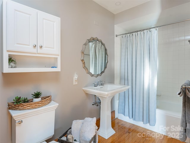 bathroom with shower / tub combo, hardwood / wood-style flooring, and toilet