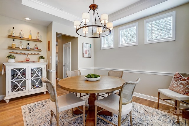 dining area with light wood-type flooring, ornamental molding, and a chandelier