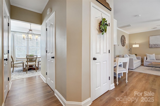 corridor featuring a chandelier, wood-type flooring, and ornamental molding