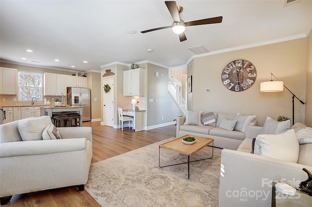 living room with ceiling fan, light hardwood / wood-style floors, sink, and crown molding