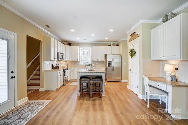 kitchen featuring a center island, white cabinets, light hardwood / wood-style flooring, a kitchen bar, and stainless steel appliances