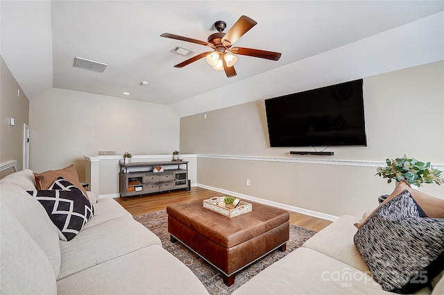 living room with hardwood / wood-style flooring, ceiling fan, and vaulted ceiling