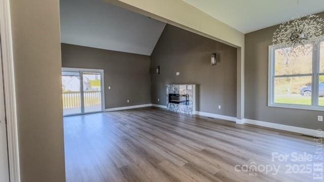 unfurnished living room featuring hardwood / wood-style floors and lofted ceiling