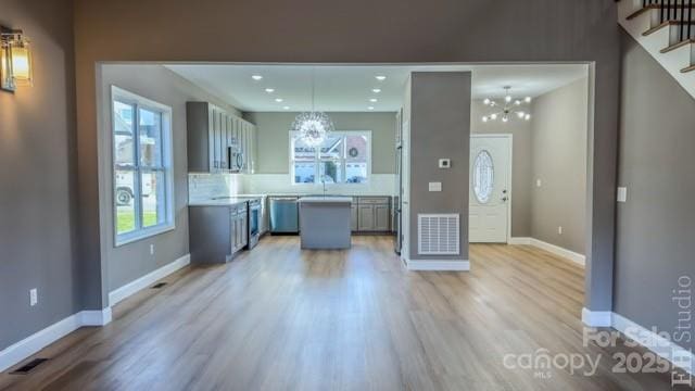 kitchen featuring hardwood / wood-style floors, gray cabinets, pendant lighting, and a chandelier