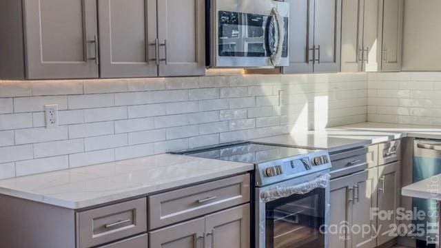 kitchen featuring gray cabinets, decorative backsplash, and appliances with stainless steel finishes