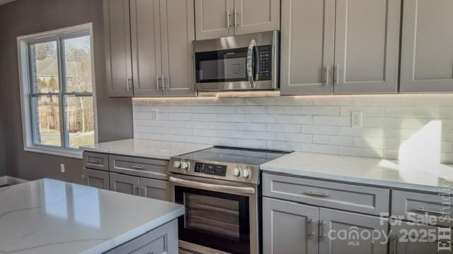 kitchen with gray cabinetry, decorative backsplash, and stainless steel appliances