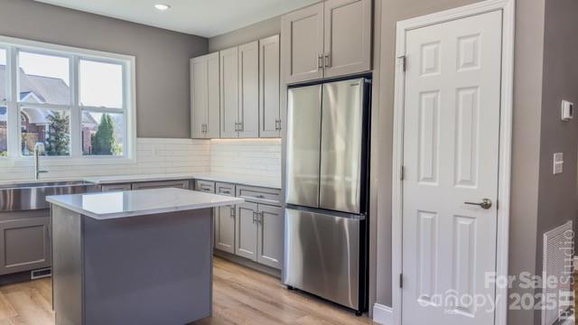 kitchen featuring gray cabinetry, a center island, light wood-type flooring, and stainless steel refrigerator