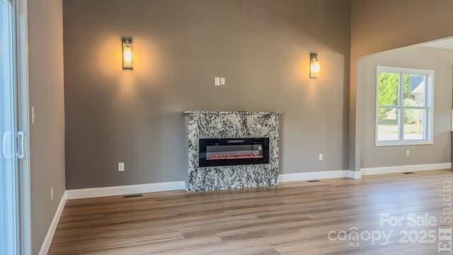 unfurnished living room with a high end fireplace and light wood-type flooring