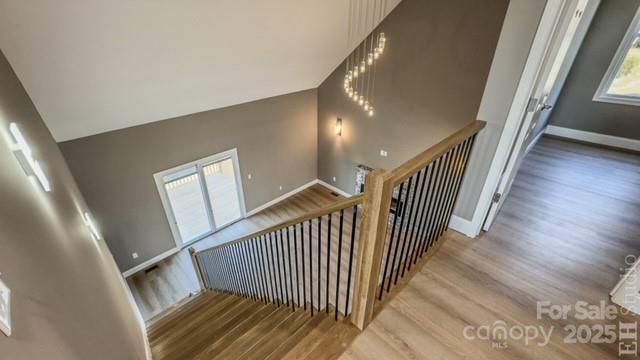 stairs featuring a healthy amount of sunlight, wood-type flooring, and high vaulted ceiling