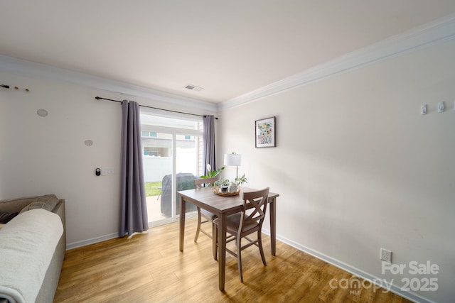 dining room featuring light hardwood / wood-style floors and crown molding