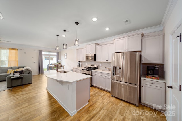 kitchen featuring sink, hanging light fixtures, an island with sink, tasteful backsplash, and stainless steel appliances