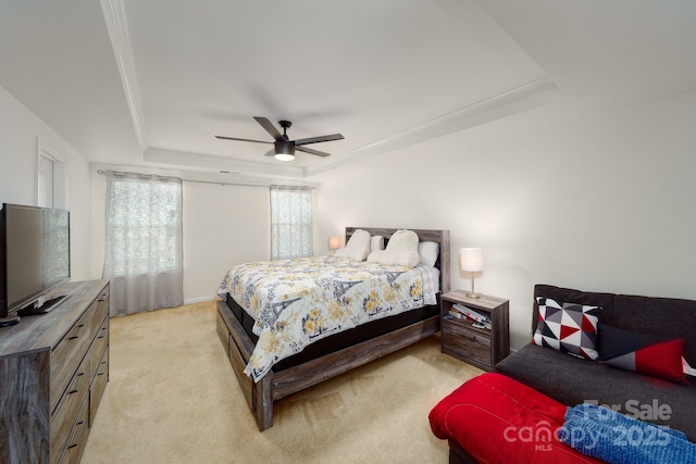 carpeted bedroom with a tray ceiling, ceiling fan, and crown molding